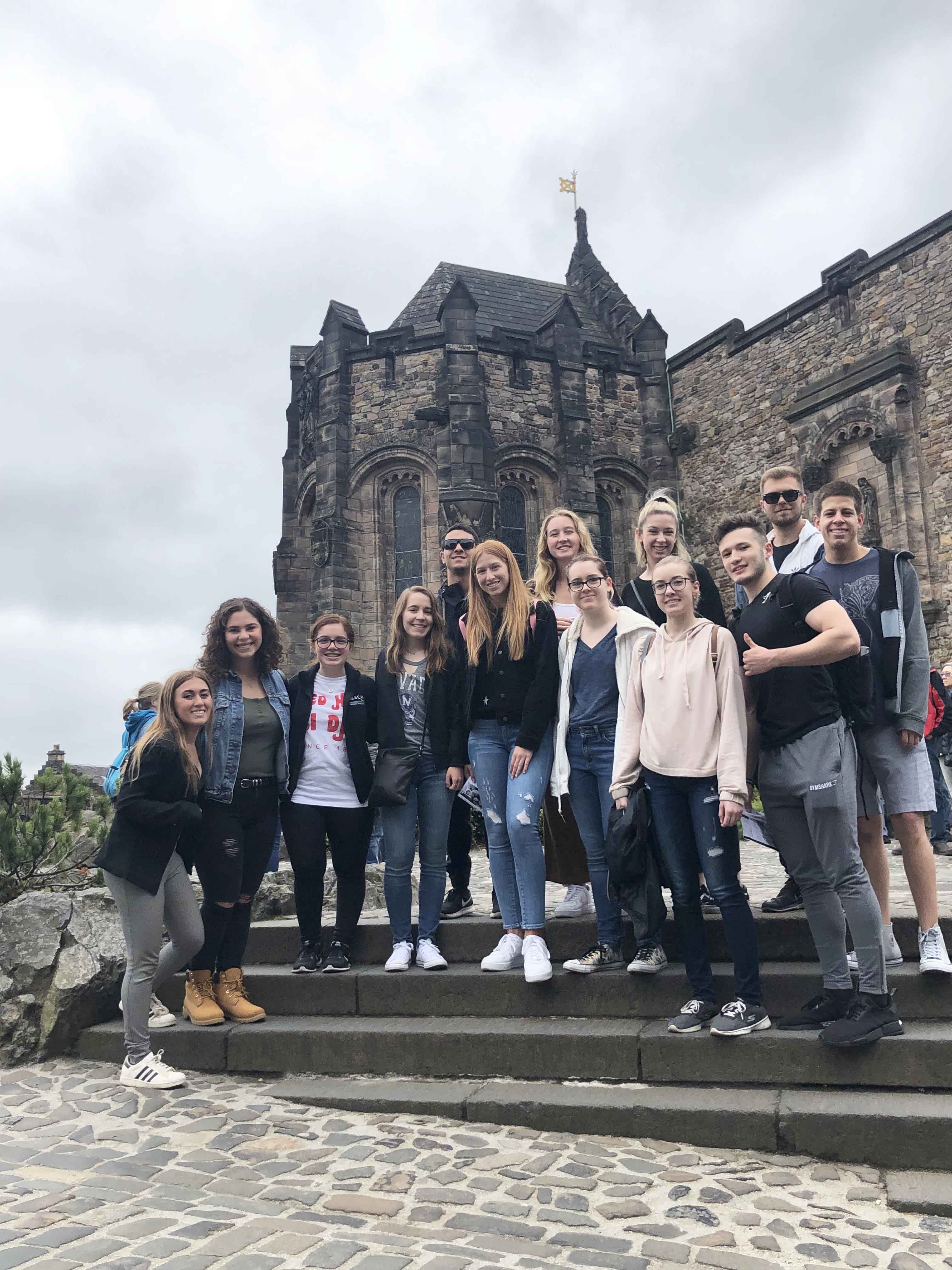 A group of students standing in front of the historic Edinburgh Castle in Edinburgh, England.