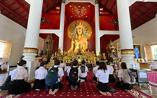 Students sitting on the ground in a Buddhist temple in Chiang Mai, Thailand.