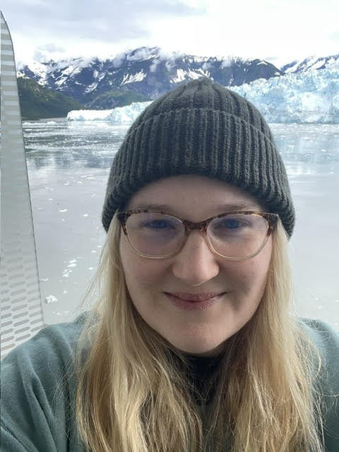 Leanne Howard wearing a beanie with snowy mountains in the background.