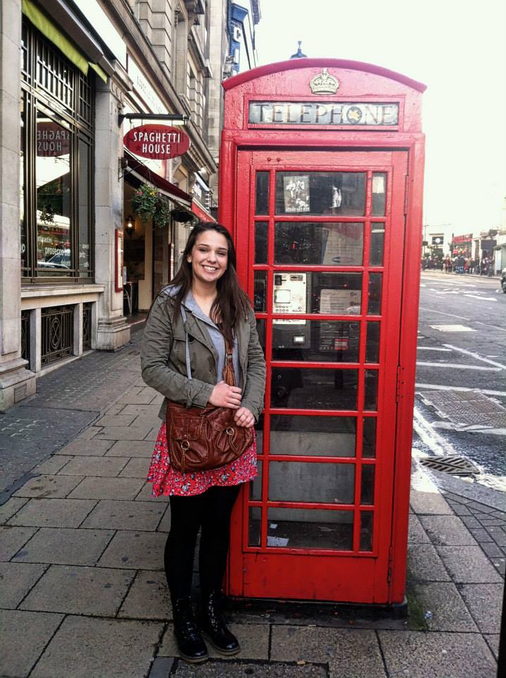 Amanda standing next to a classic red phone booth in London.