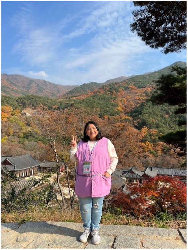 Angelica standing in a pink vest overlooking the rolling hills in South Korea.