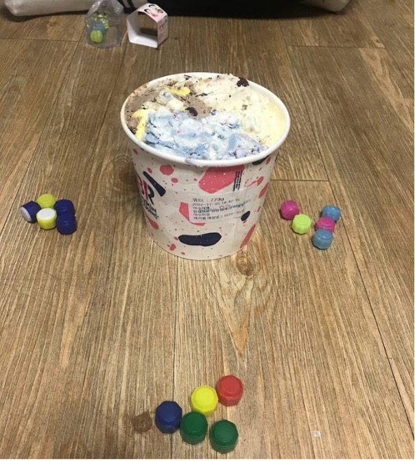 An ice cream pint sitting on the floor with game pieces around it.