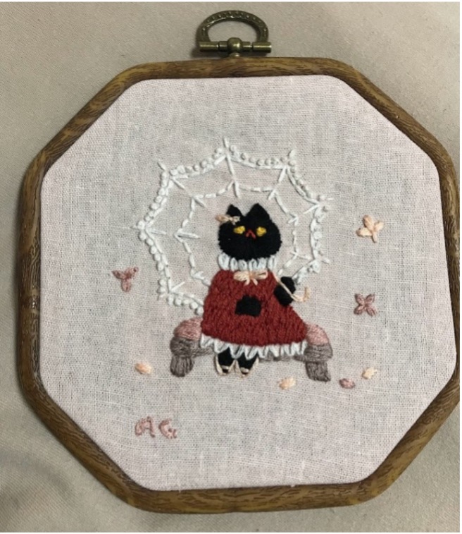 An embroidery of a cat in a dress.