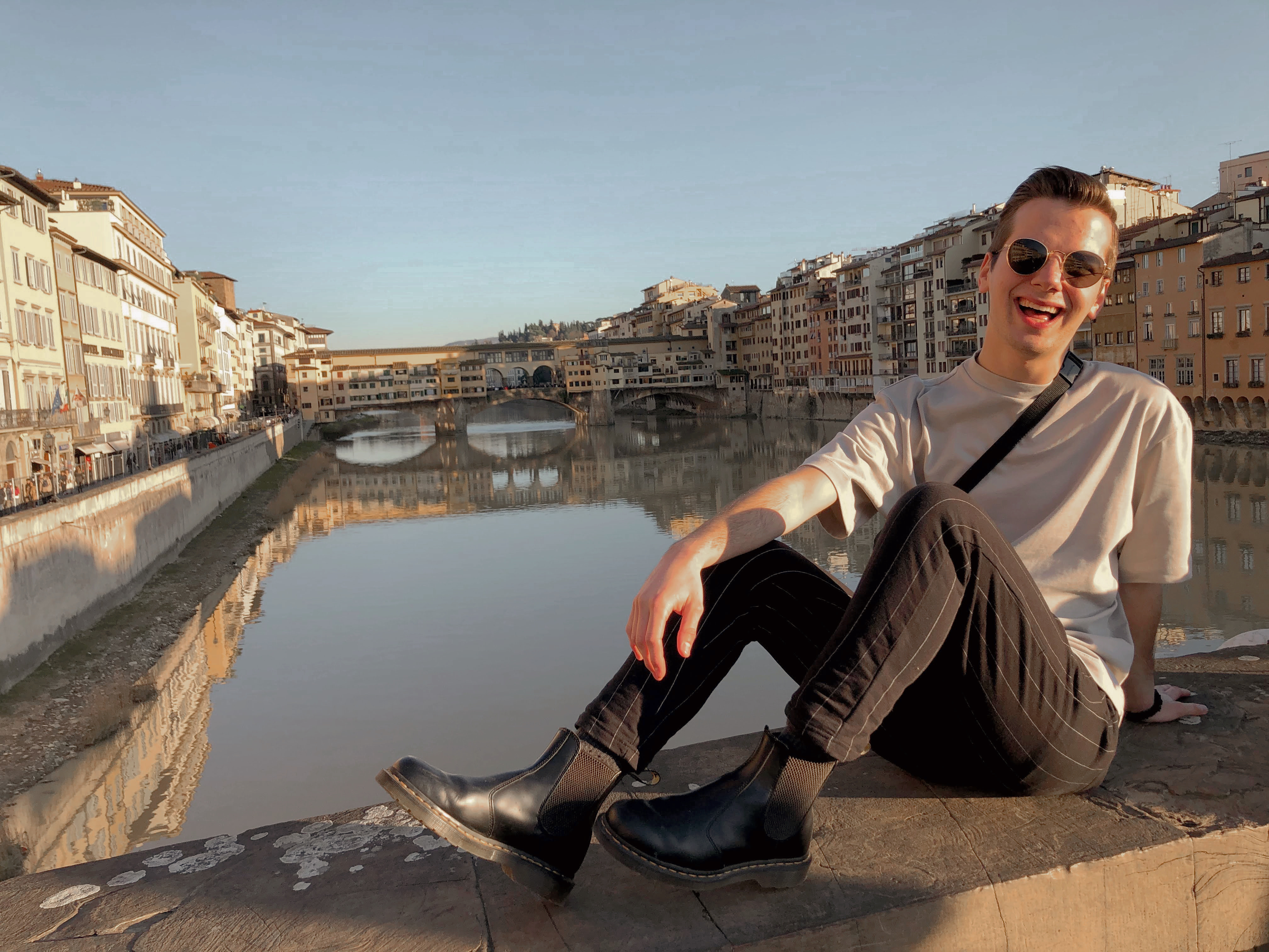 Danny sitting on a bridge overlooking a canal in Italy.