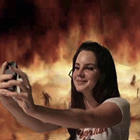 A meme of a person taking a selfie with a fire behind them.