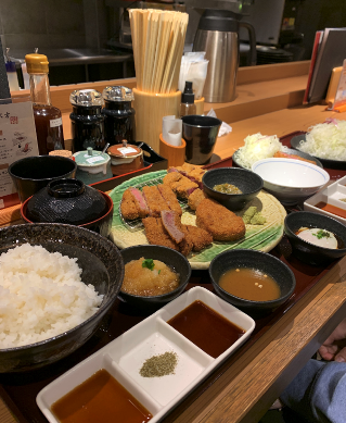 Gyukatsu on a table with different sauces next to it in Japan.