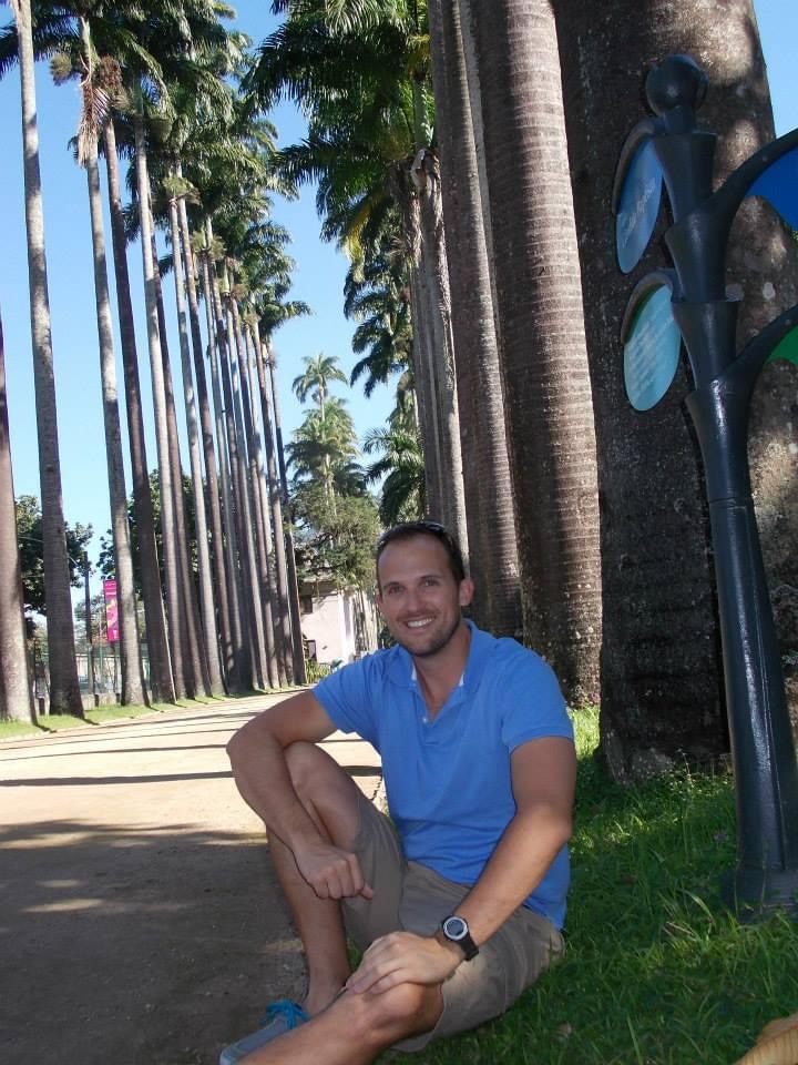 Thomas sitting with a row of palm trees behind him in Rio de Janeiro, Brazil.