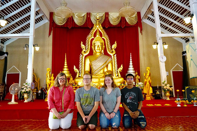 Phoebe kneeling with friends in a Thai Wat in Thailand.