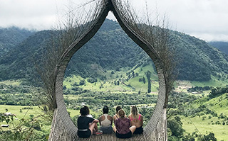 Students sitting in a large stick structure overlooking a valley in Costa Rica.