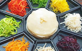 Top view of traditional Korean food set on a divided black platter.