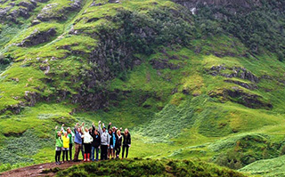 Students standing on a grassy mountain while hiking in Scotland. 