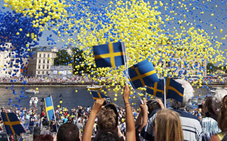 Students holding Swedish flags with confetti in the air at a celebration in Sweden.