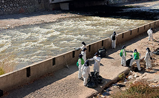 A group of students cleaning up trash along a river in Santiago, Chile.