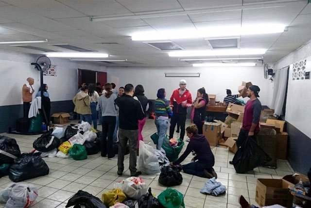 A group of students conducting a supply drive standing in a room with donated items in Costa Rica.