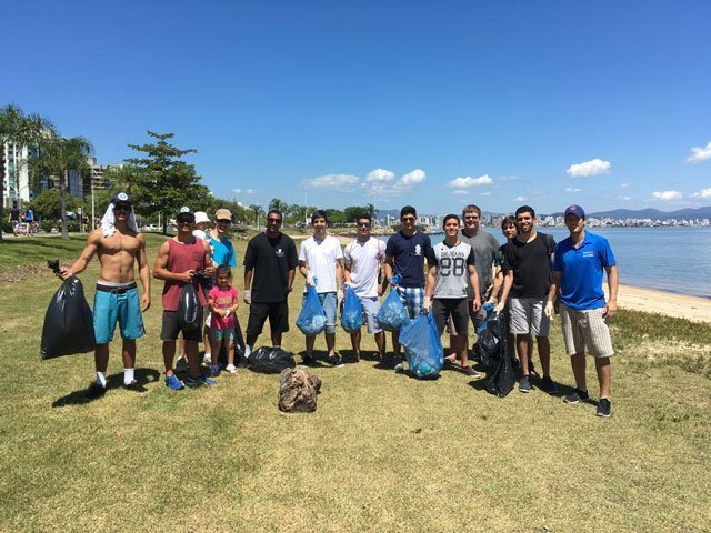 A group of students holding trash bags doing a clean up on a beach.