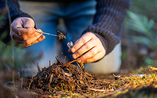 A close up image of two hands putting dirt into a lab tube to test.