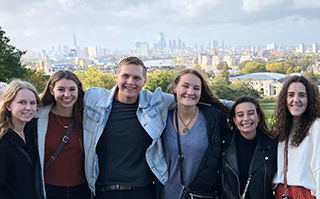 Six people standing together with a view of London, England in the background.