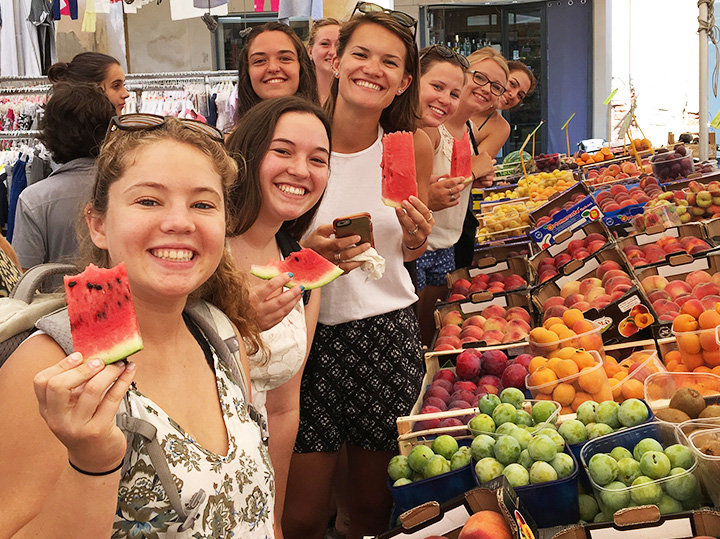 Students holding fruit at a farmers marketing in Reggio Emilia, Italy.