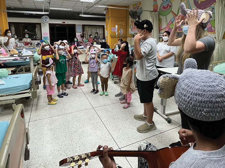 Students singing and playing music for children with cancer in a hospital in Thailand.