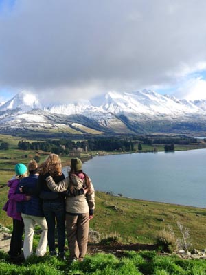 Four people standing on a mountain looking off to the distance in New Zealand.