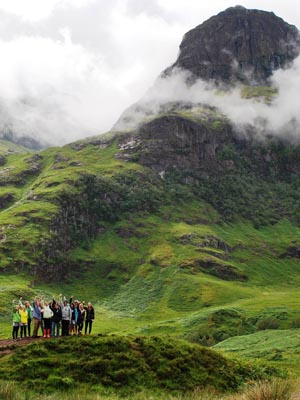 Students on a lush green mountain while on a hike in Scotland.