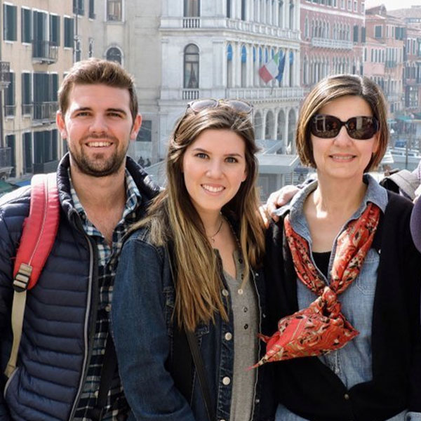 Three students posing together with historic buildings in the background.