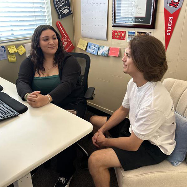 A student sitting down at a desk with a USAC advisor.