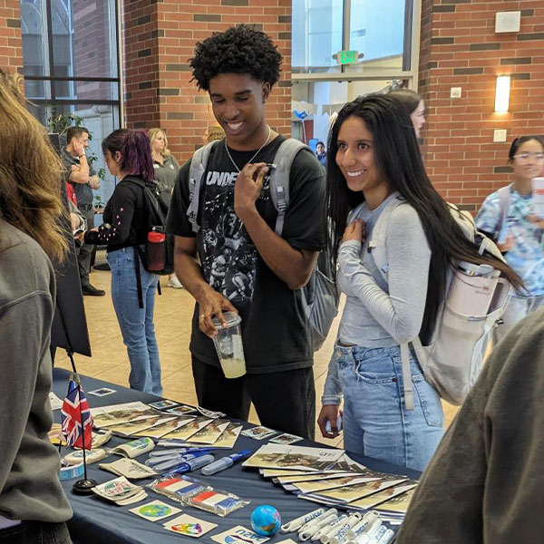 Two students at a USAC tabling event learning about studying abroad.