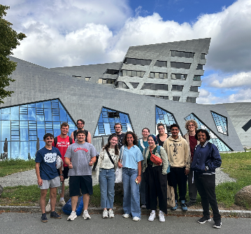 A group of students standing in front of the Liebeskind building on the Leuphana University campus in Lüneburg, Germany.