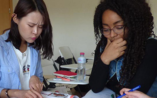 Two students looking over paperwork at a table.