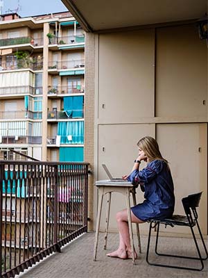 Student sitting on their balcony with their laptop while studying abroad.