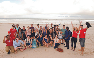 A large group of people posing together on a beach.
