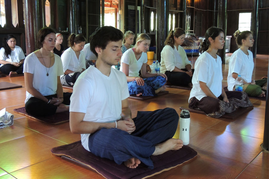 Students sitting on the floor meditating. 