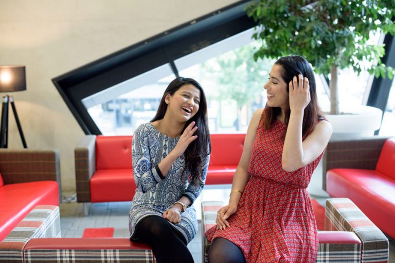 Friends sitting on a couch laughing.