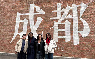 Four people standing in front of Chinese calligraphy street art in Chengdu, China.