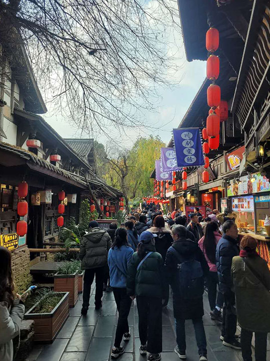 People walking down a historic street in Chengdu, China.