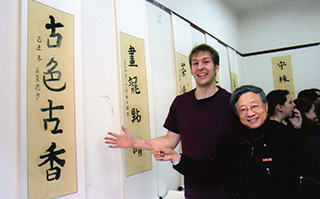 Two people standing in front of traditional Chinese calligraphy art in Shanghai, China.
