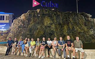 Students sitting beneath a sign that says Cuba.