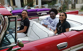 Three people sitting in a classic car in La Habana, Cuba.