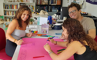 Three students at a table writing on a posterboard.