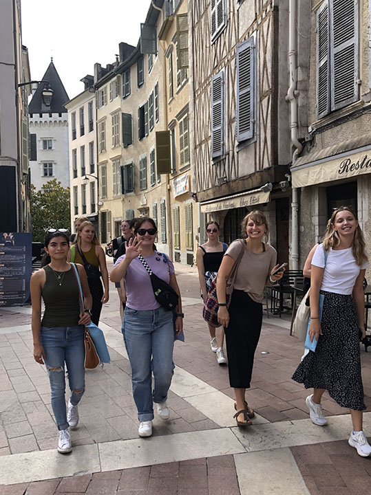 Students walking down cobblestone streets lined with historic buildings in Pau, France.