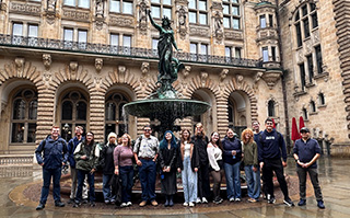 A group of students in front of a fountain and historic building in L&uuml;neburg, Germany.