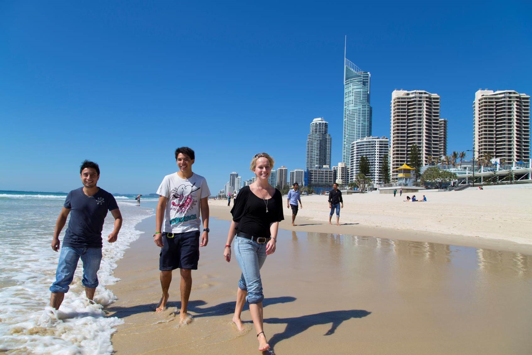 Three students walking along the beach in Gold Coast, Australia.
