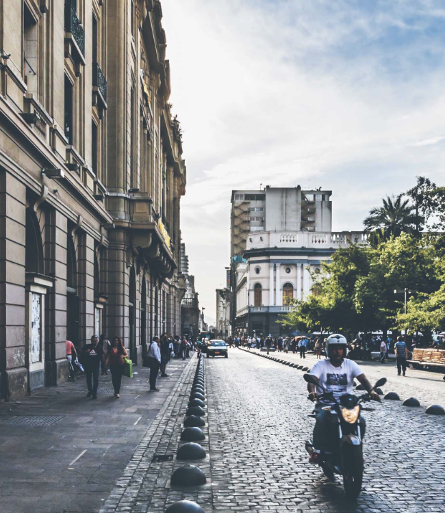 Person riding a motorcycle on the cobblestone streets in the city of Santiago, Chile.