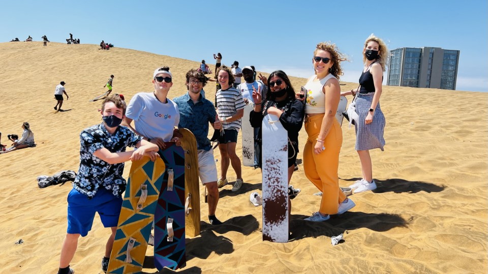 Students standing in the dunes with sandboards in Viña del Mar.