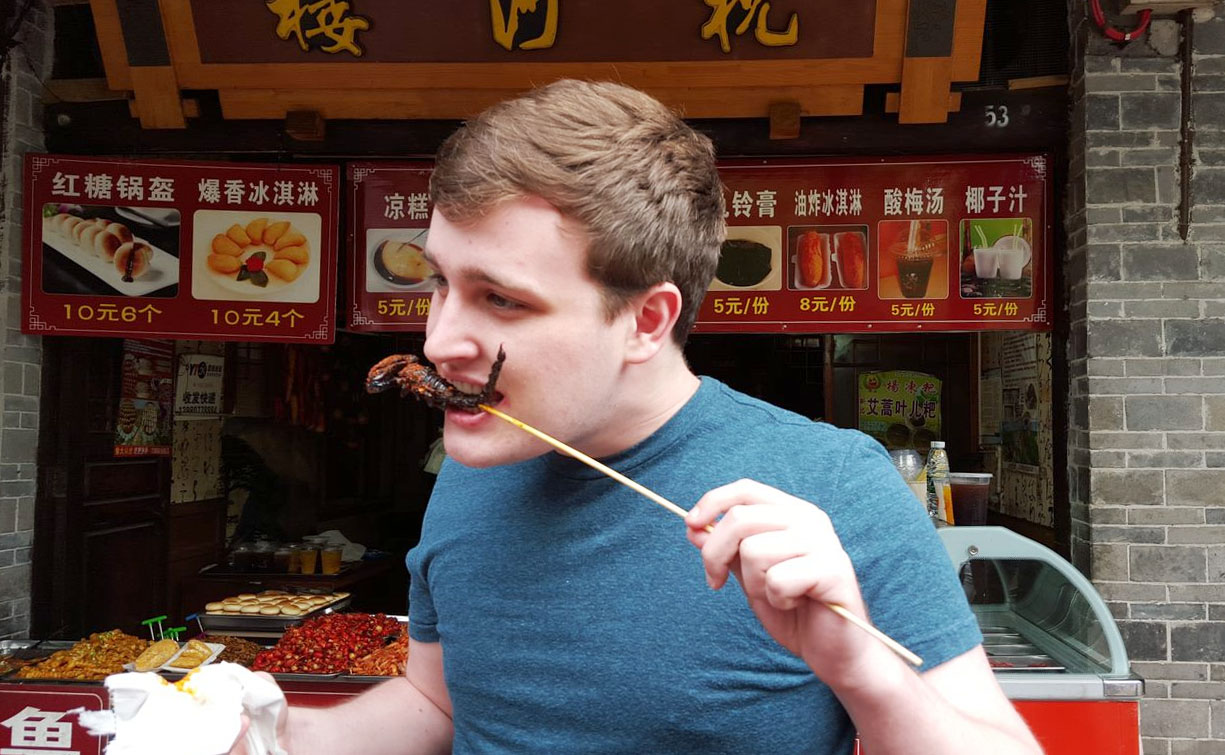A student eating a Sichuan fried scorpion in Chengdu, China.