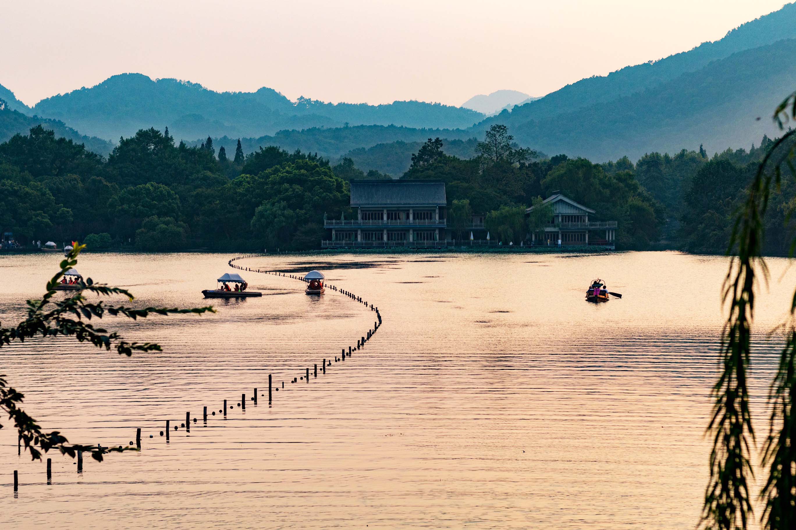 View of the water and mountains at sunset in Hangzhou, China.