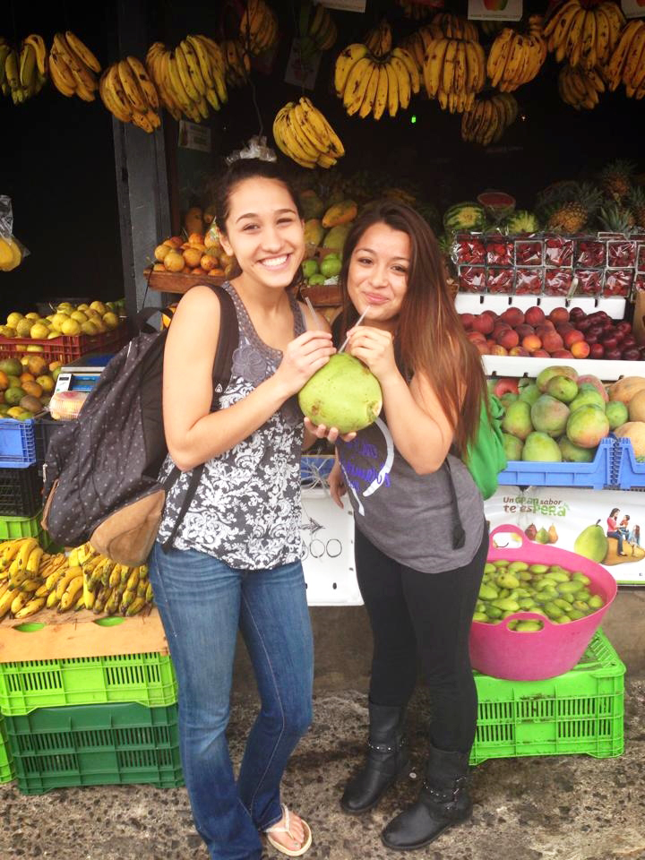 Students enjoying a fresh drink from a coconut at the market in Heredia, Costa Rica.