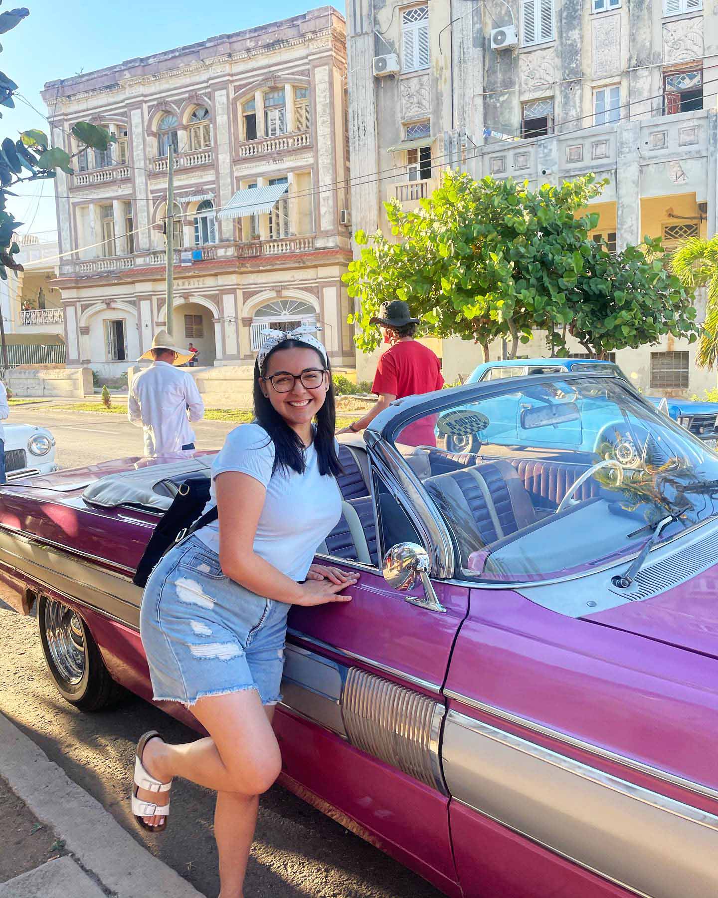 Student posing in front of a classic car in La Habana, Cuba.