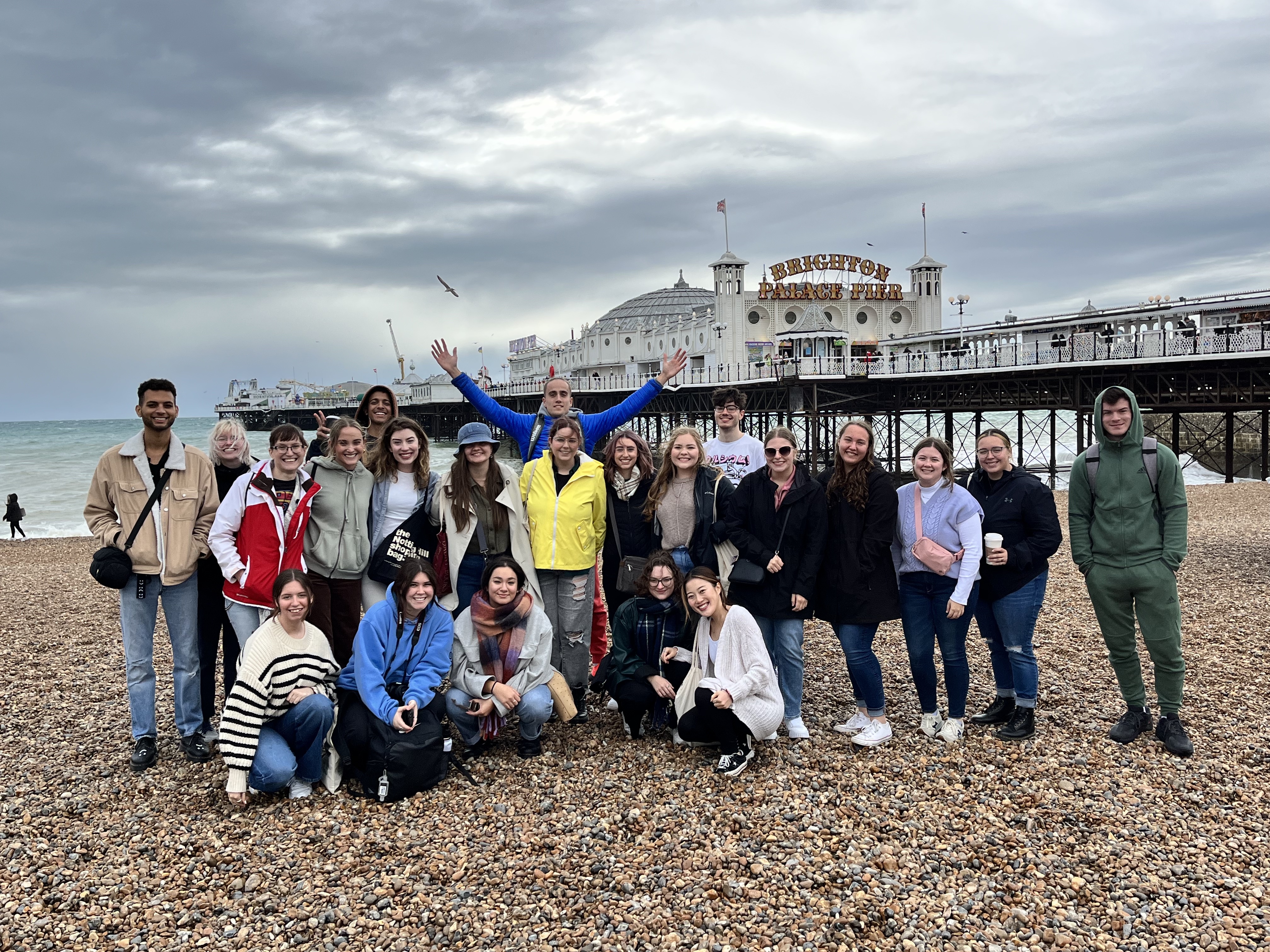 A group of students on the beach with Brighton Palace Pier in the background in Brighton, England
